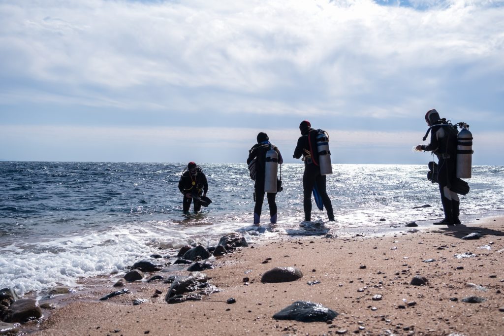 silhouettes of scuba divers on the seashore depth explorers prepare to dive to the bottom